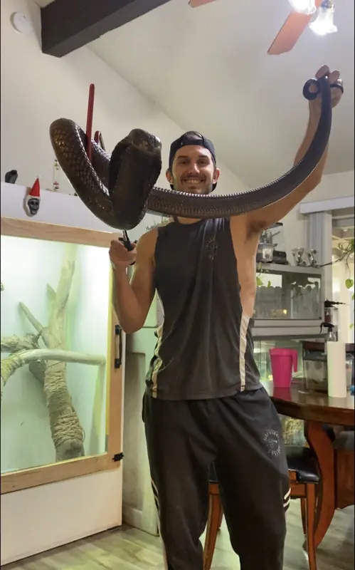 Tyler holding a black snake overhead