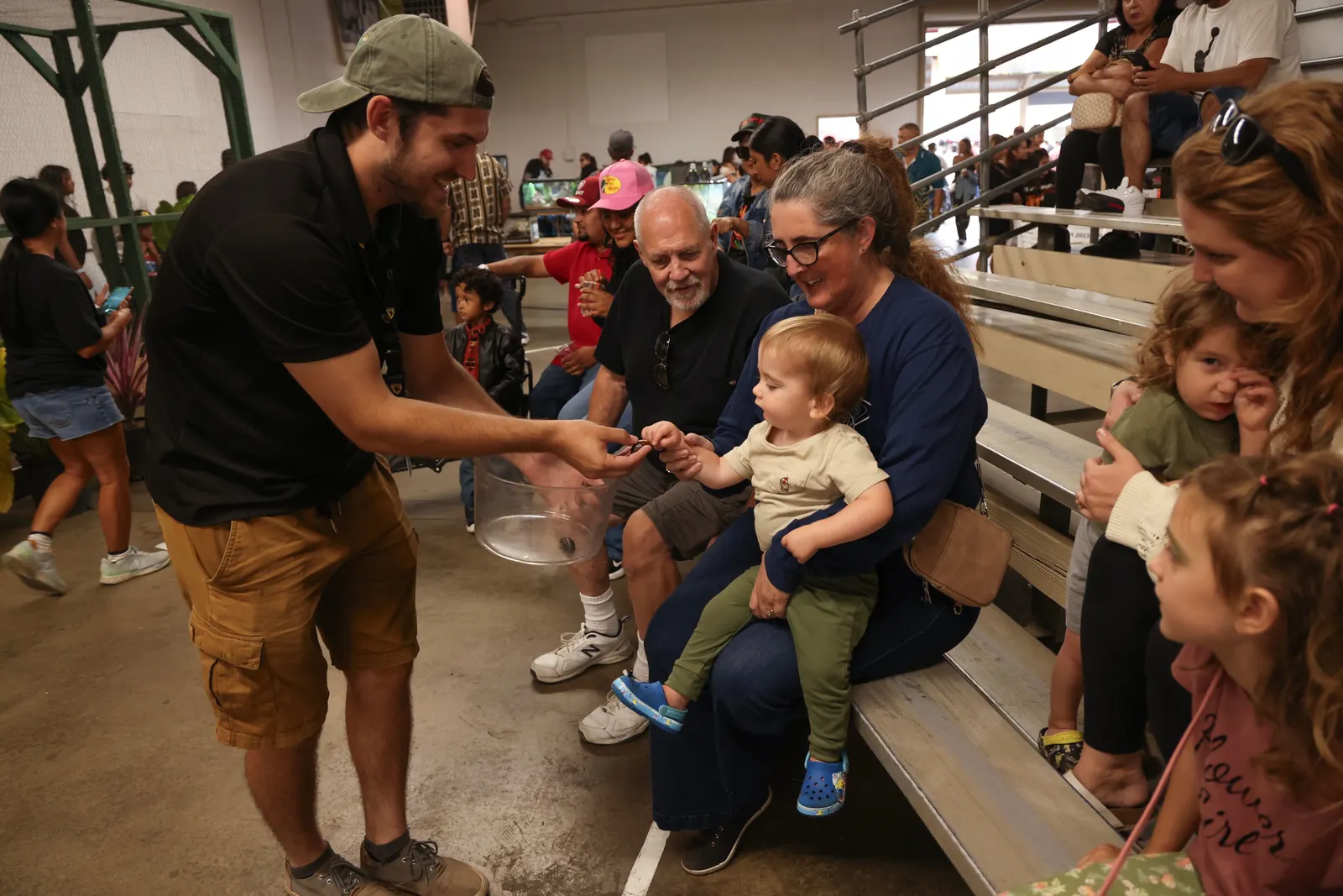 Tyler handing a lizard to kids in the bleachers at a reptile show
